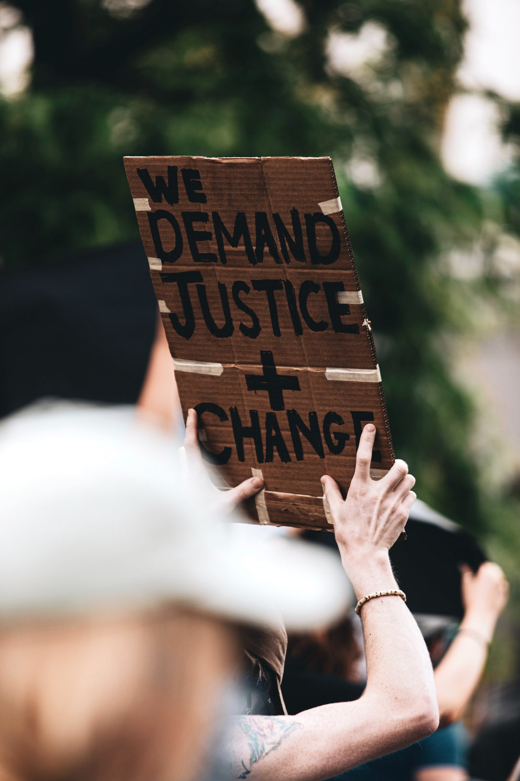 manifestant brandissant une pancarte avec l'inscription (anglais) "nous demandons la justice + le changement"